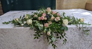 Ein wunderschöner Blumenstrauß mit zarten Rosen und frischem Grün auf einem eleganten Tisch.