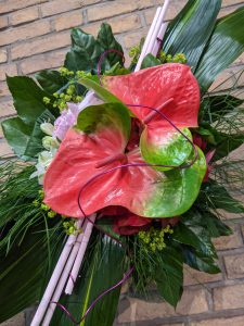 Ein wunderschöner Blumenstrauß mit leuchtenden Anthurien und frischem Grün, perfekt für jeden Anlass.