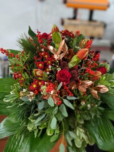 Ein wunderschöner Blumenstrauß mit roten Rosen, Beeren und grünen Blättern für jeden Anlass.