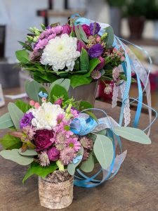Bunte Blumenarrangements mit Schleifen in einer rustikalen Umgebung, perfekt für jeden Anlass.