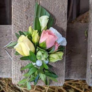 Ein schöner Blumenstrauß mit bunten Rosen und frischem Grün auf einem Holztisch.