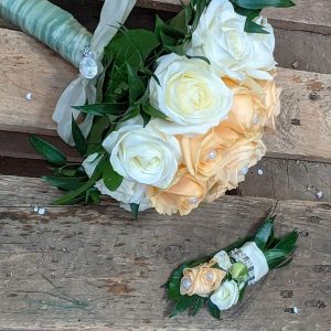 Ein wunderschöner Brautstrauß mit weißen und pfirsichfarbenen Rosen auf Holzuntergrund.