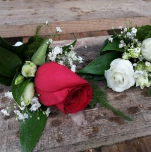 Schöne rote und weiße Rosen mit zarten Blumenarrangements auf rustikalem Holz.